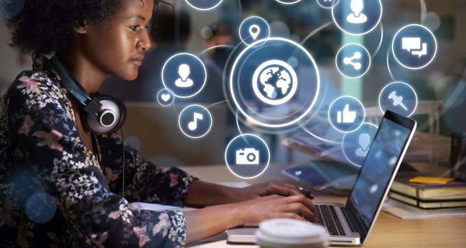 Mulher utilizando o notebook com diversos ícones luminosos sobrepostos a tela.