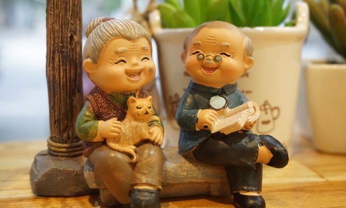 Boneco de casal de ideosos sentados em banco no parque.